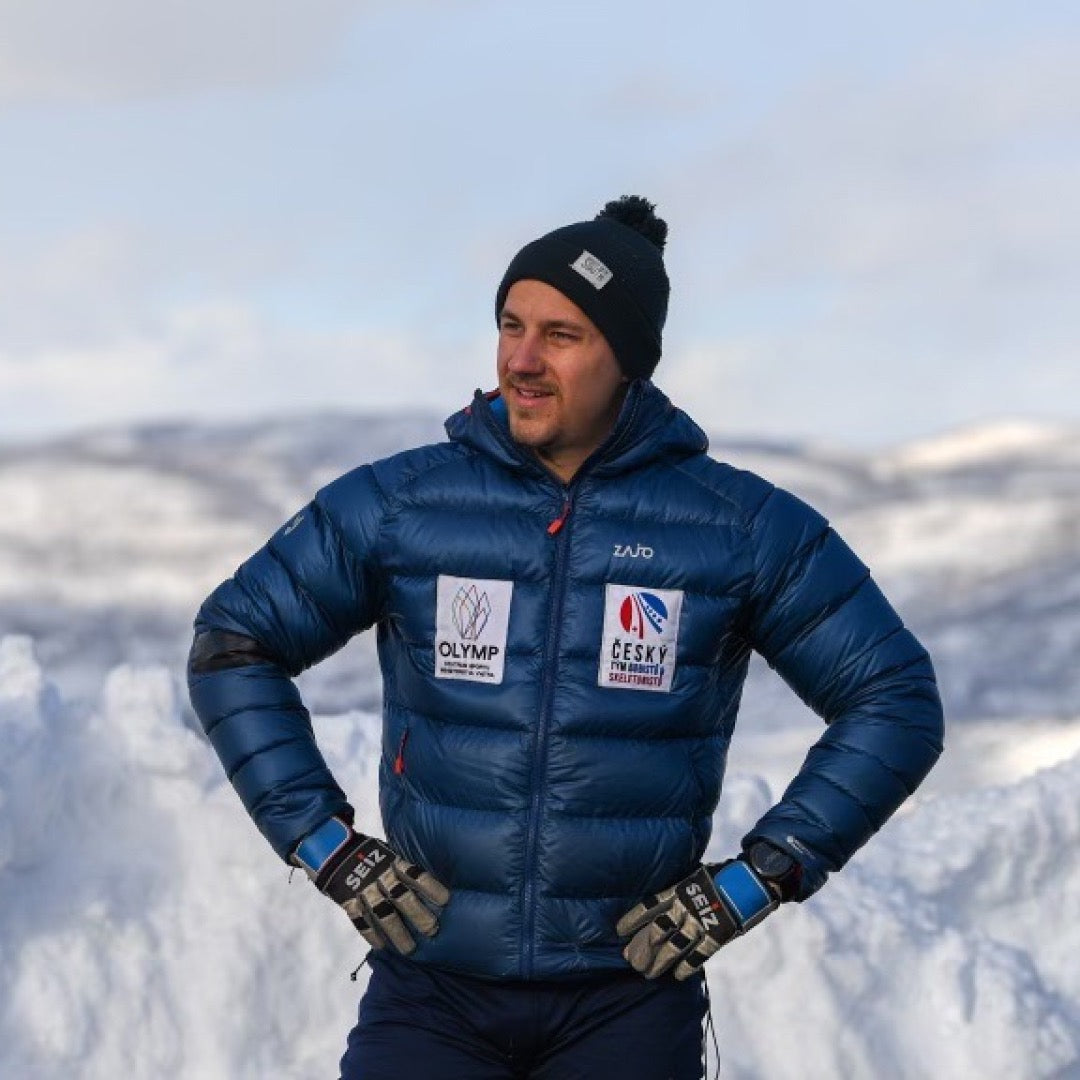 Adam posing in mountains wearing a blue winter jacket